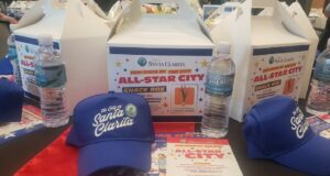 A table with City of Santa Clarita lunchboxes and hats placed on top of it