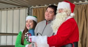 Ethan Derick, middle, poses with Santa Claus and an elf at Carousel Ranch's Santa Day in Santa Clarita, Calif. on Dec. 10, 2022. Zena Taher/ KHTS News