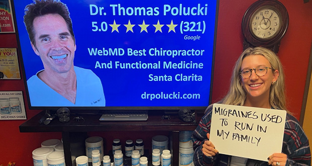 Smiling young woman holding sign in Santa Clarita Chiropractor’s office “Migraines used to run in my family”