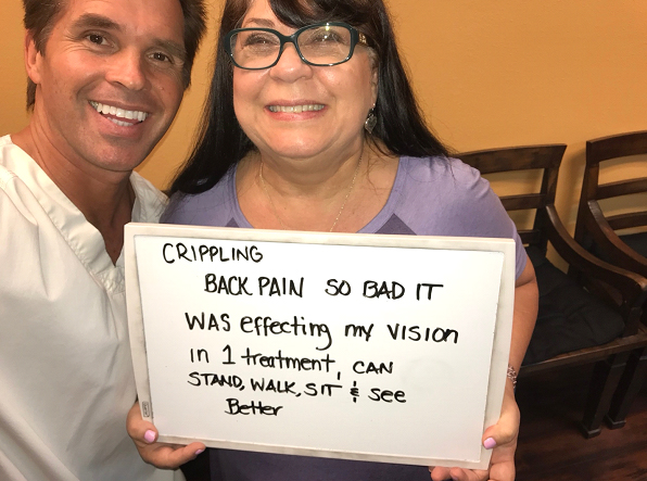 Engineer holding sign “Back Pain So Bad It Was Effecting My Vision, In 1 Treatment I Can Stand, Walk, Sit, And See Better” after upper-cervical alignment and Instalign Massage™ at Dr. Polucki’s office.